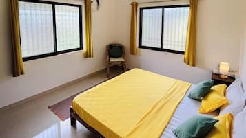 A bedroom with a bed, two windows, an air conditioner, a ceiling fan, and a chair.