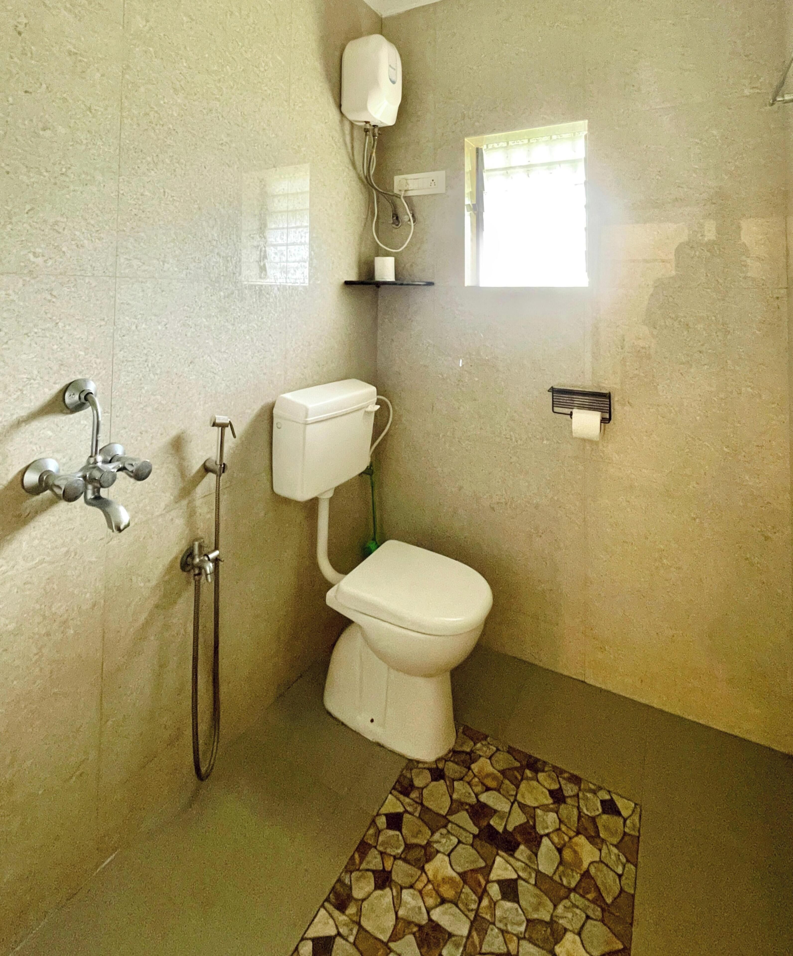 A bathroom with a toilet, a shower, and a window.