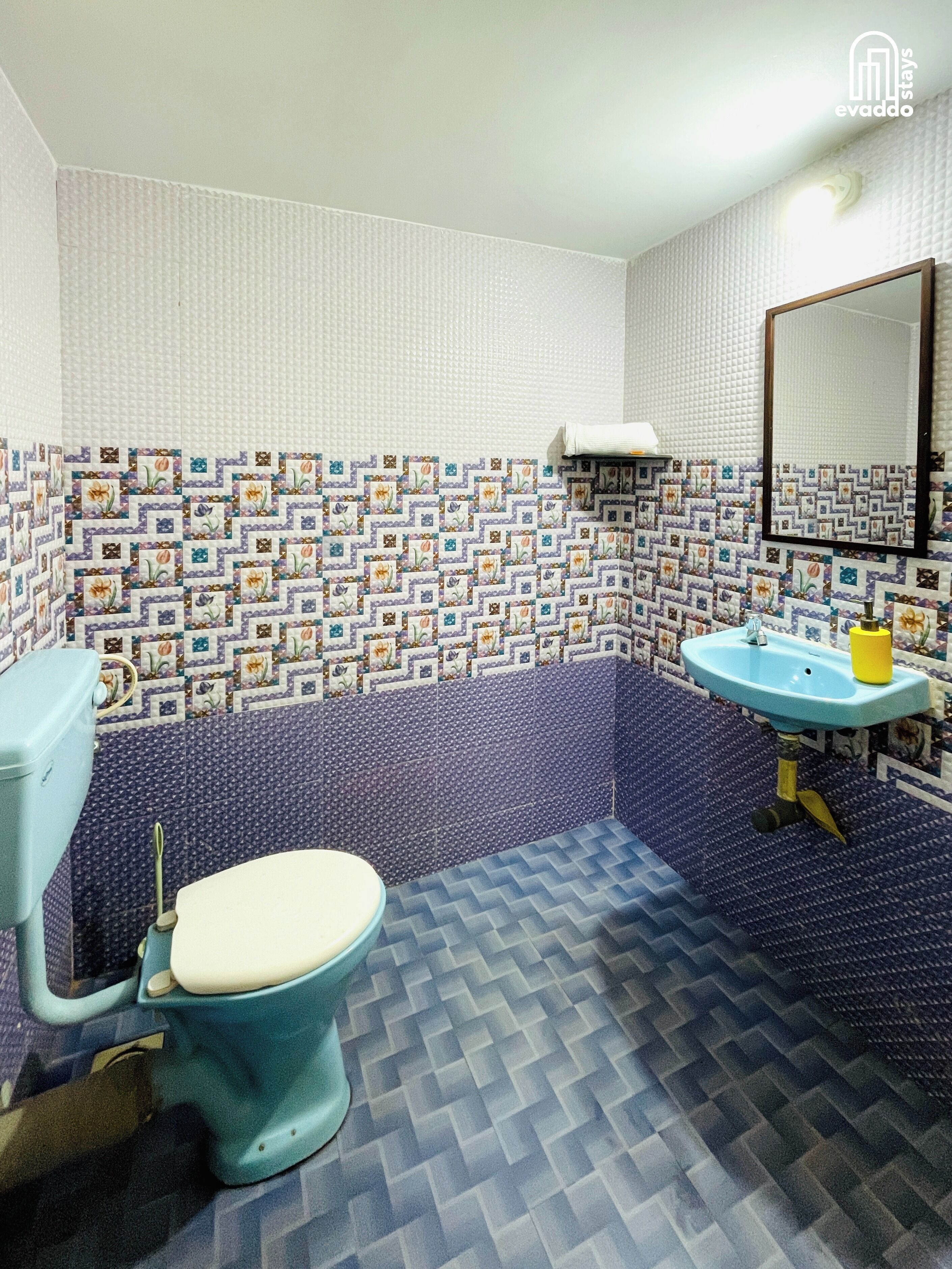 A bathroom with a toilet, sink, and patterned walls.