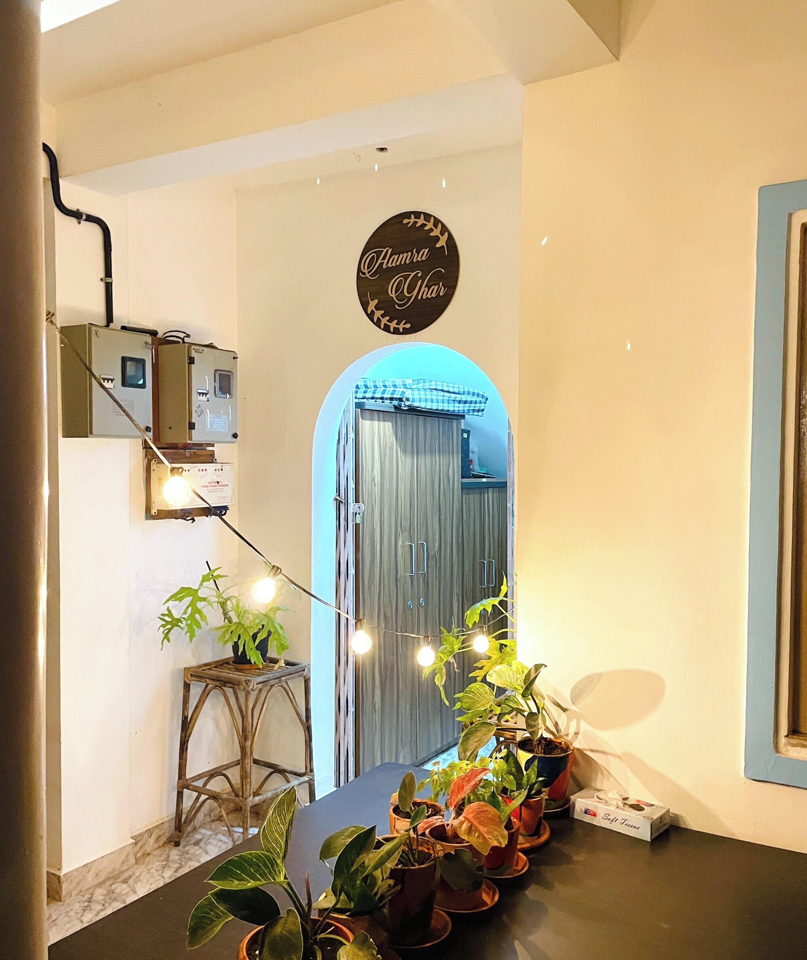 A hallway with a wooden sign, a potted plant, a light fixture, and a door.