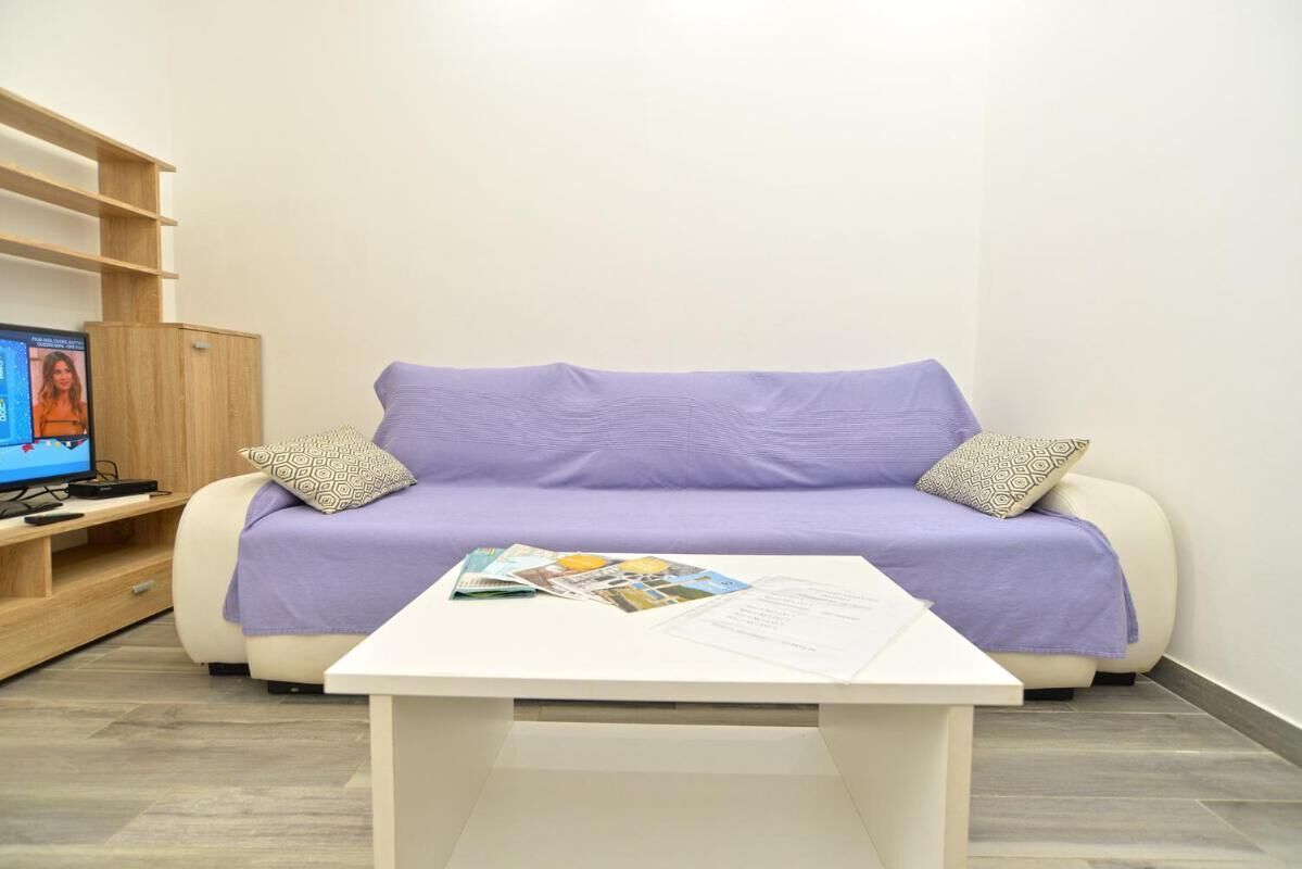 A modern living room with a sofa, a coffee table, and a TV on a stand.