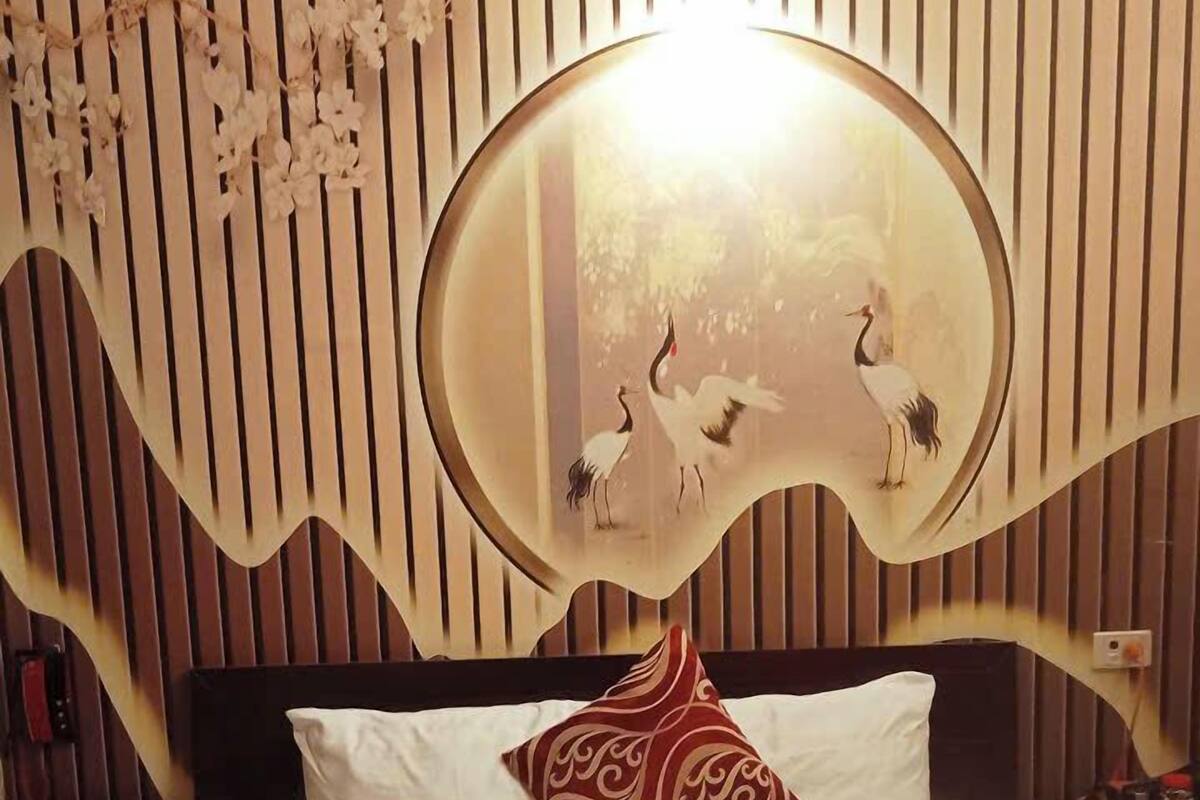 Een hotelkamer met een bed, een decoratieve spiegel en een nachtkastje met een lamp.