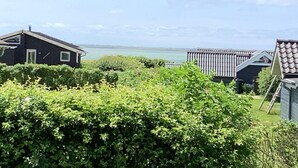 Vue d’une propriété située sur la côte, avec une maison et une terrasse en bois donnant sur la mer.