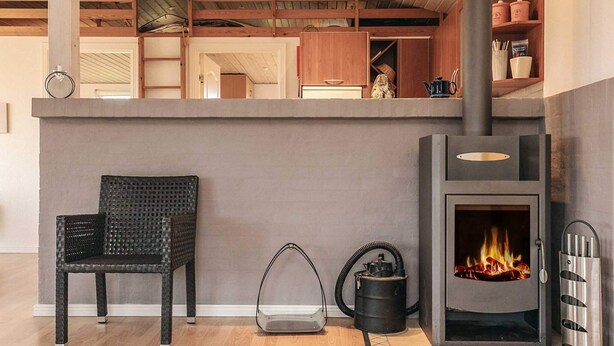 Une cuisine moderne équipée d’un poêle à bois encastré, d’une chaise en osier et d’un aspirateur.
