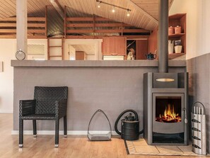 Eine moderne Küche mit eingebautem Holzofen, einem Korbstuhl und einem Staubsauger.