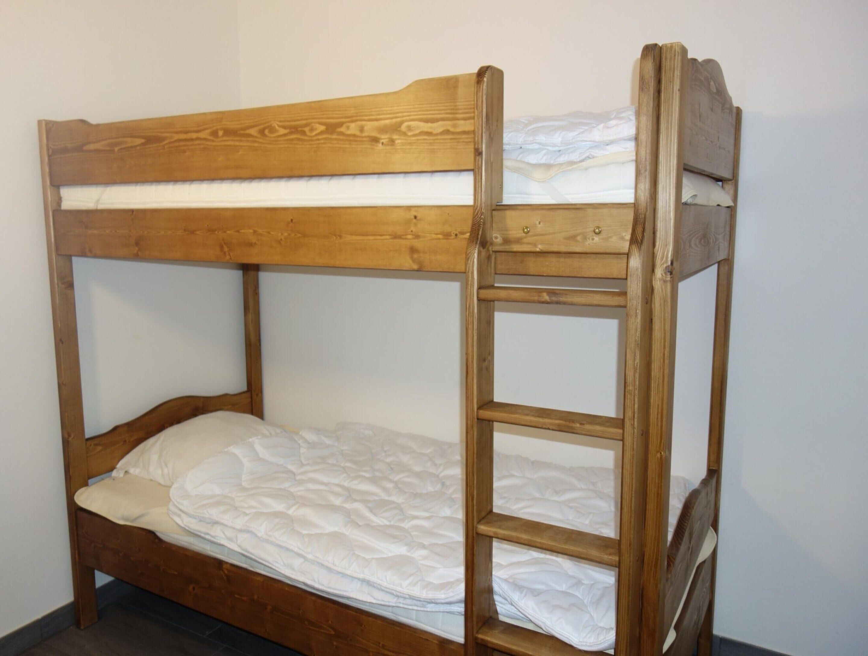 Una cama litera con estructura de madera y ropa de cama blanca.