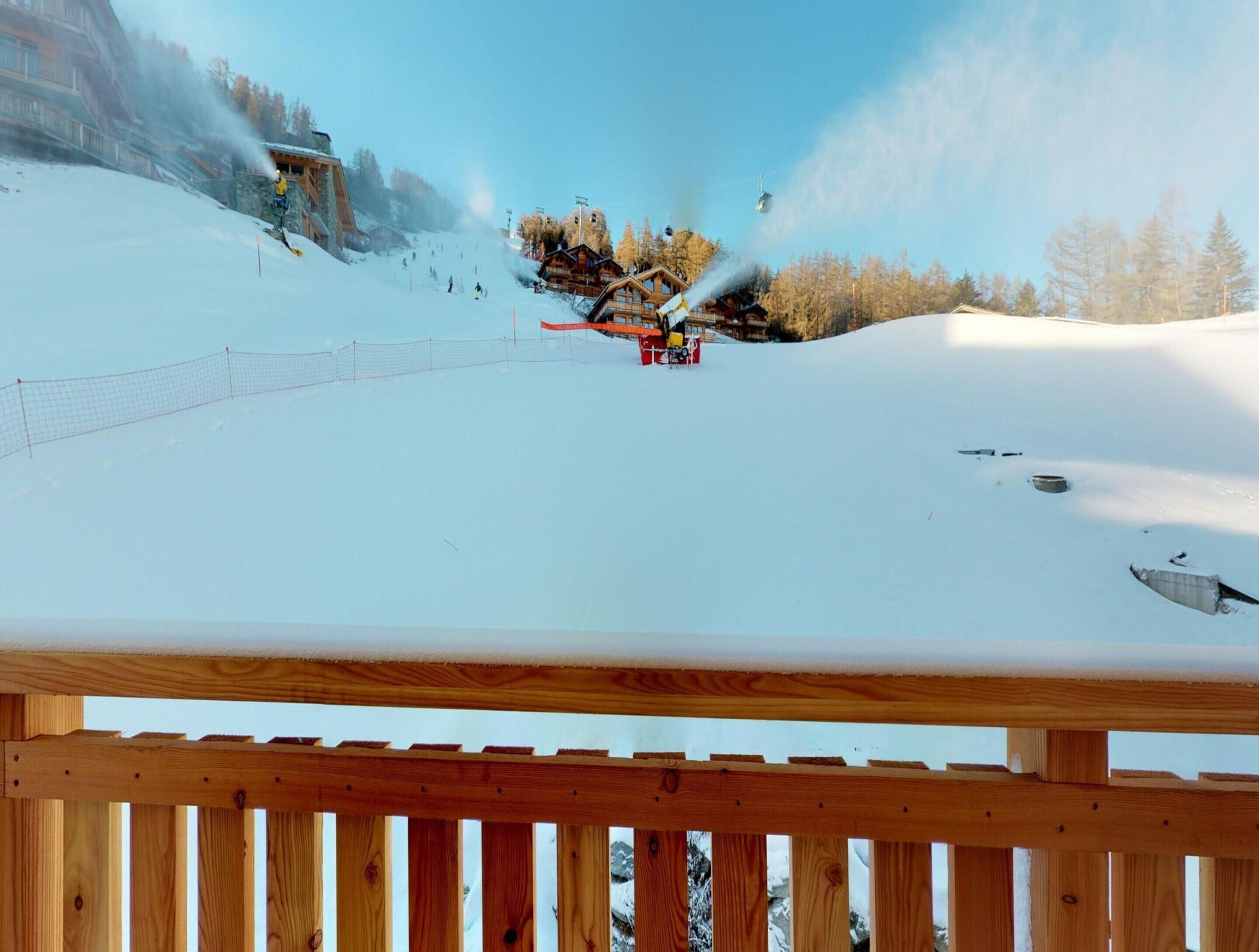 A ski slope with a wooden fence in the foreground.