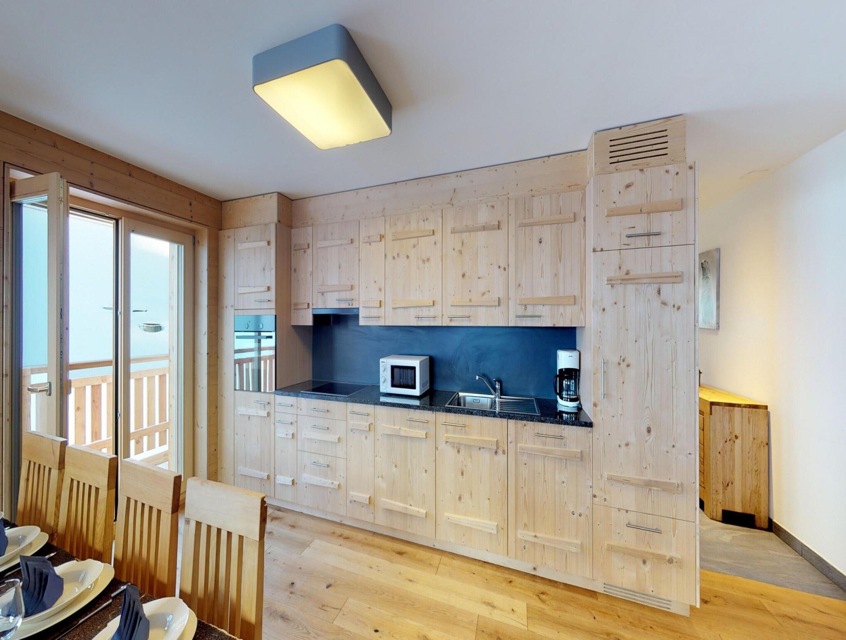 Une cuisine moderne avec des meubles en bois, un four à micro-ondes, une machine à café et une grande fenêtre.
