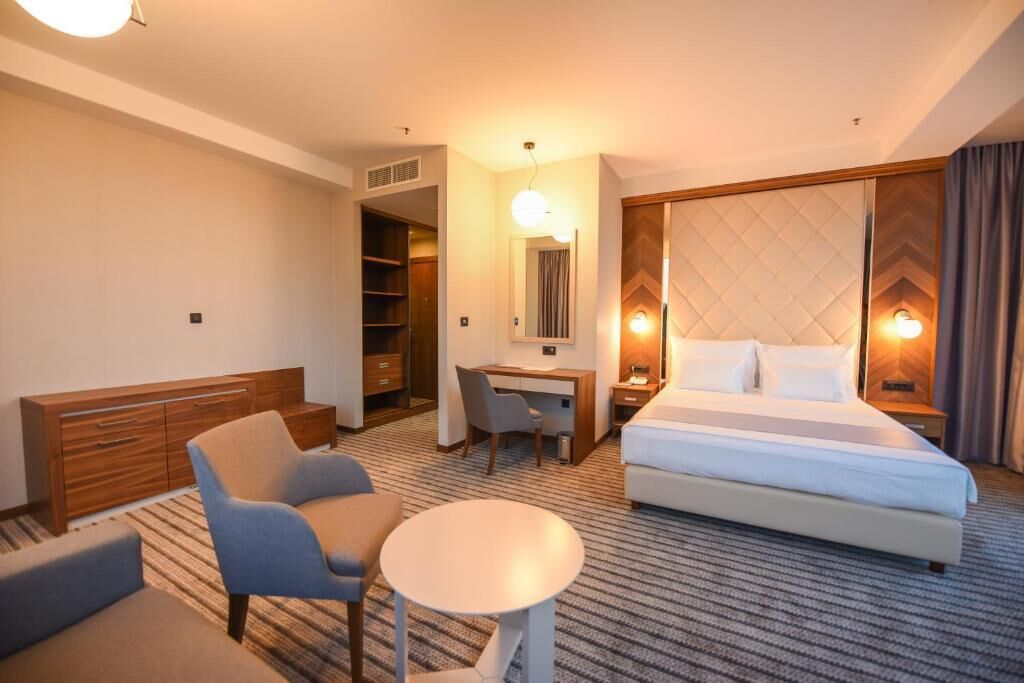 Habitación de hotel con cama, escritorio, silla, mesita y armario.