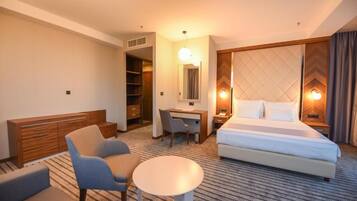 Habitación de hotel con cama, escritorio, silla, mesita y armario.