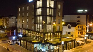 Ein modernes Hotel mit Glasfassade, mehreren Etagen und einer Dachterrasse.