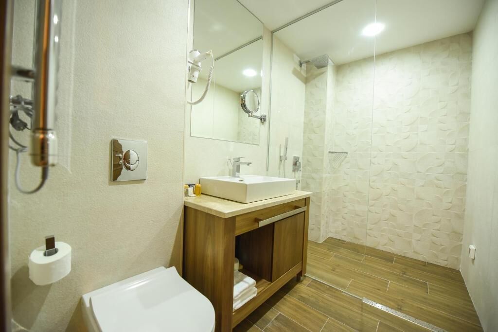 Un baño con inodoro, lavabo, espejo y ducha.