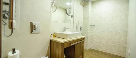 Un baño con inodoro, lavabo, espejo y ducha.