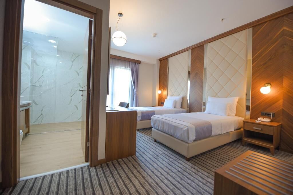 A hotel room with a large bed, a smaller bed, a desk, and a shower area.