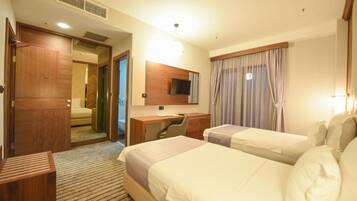 A hotel room with two beds, a desk, a chair, a TV, and a wardrobe.
