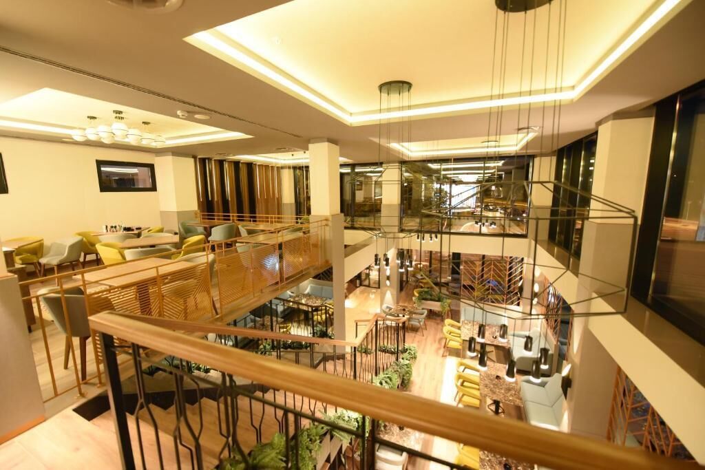 Un vestíbulo de hotel moderno con un diseño espacioso, una escalera central y varias zonas de estar.