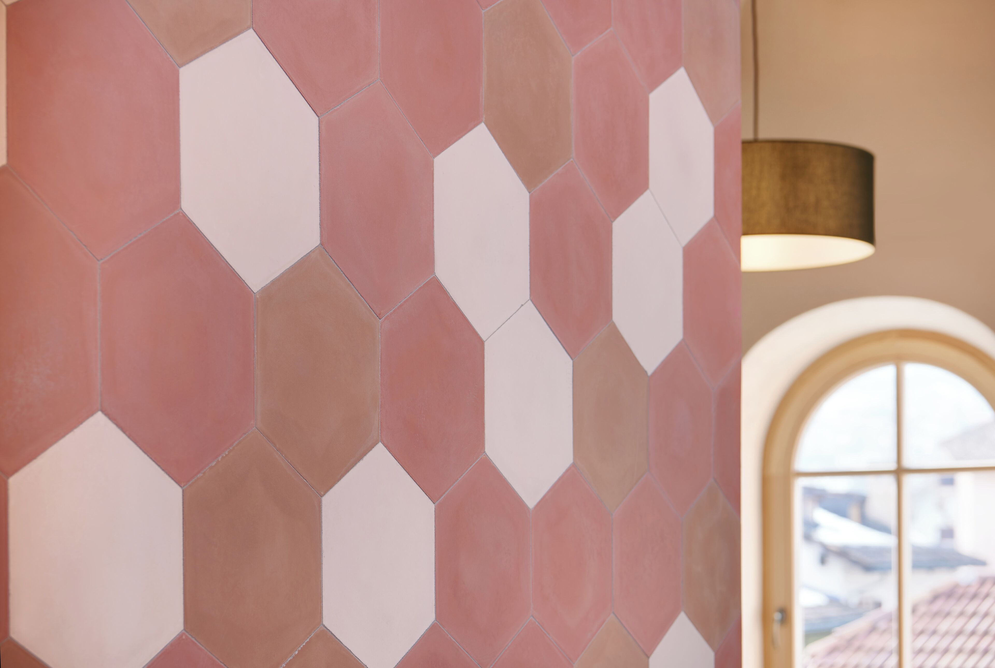 A wall with hexagonal tiles in shades of pink and white.