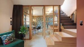 A modern interior with a staircase, a dining area, and a green sofa. - Goldengel Suiten im Herzen von Kaltern (Caldaro Sulla Strada del Vino)