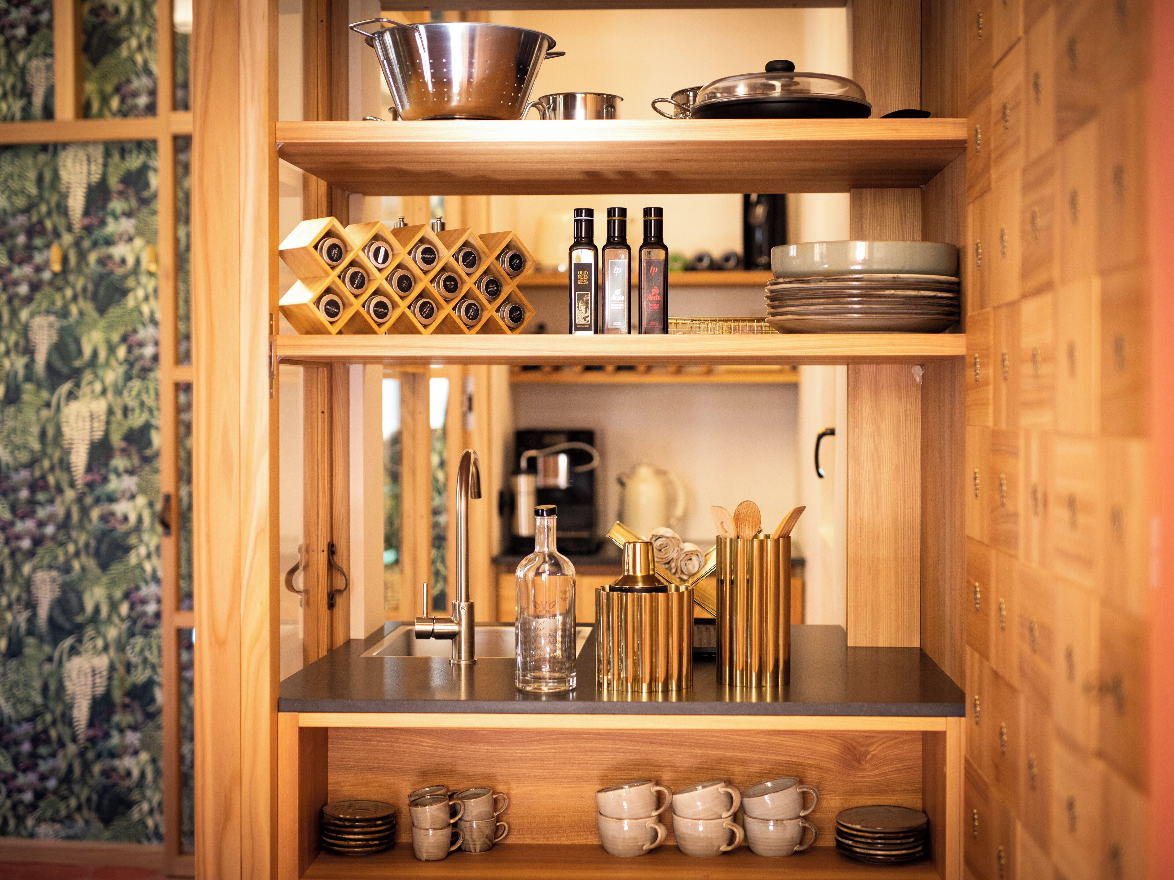 Una cocina con armarios de madera, un lavamanos de acero inoxidable y una bodega.