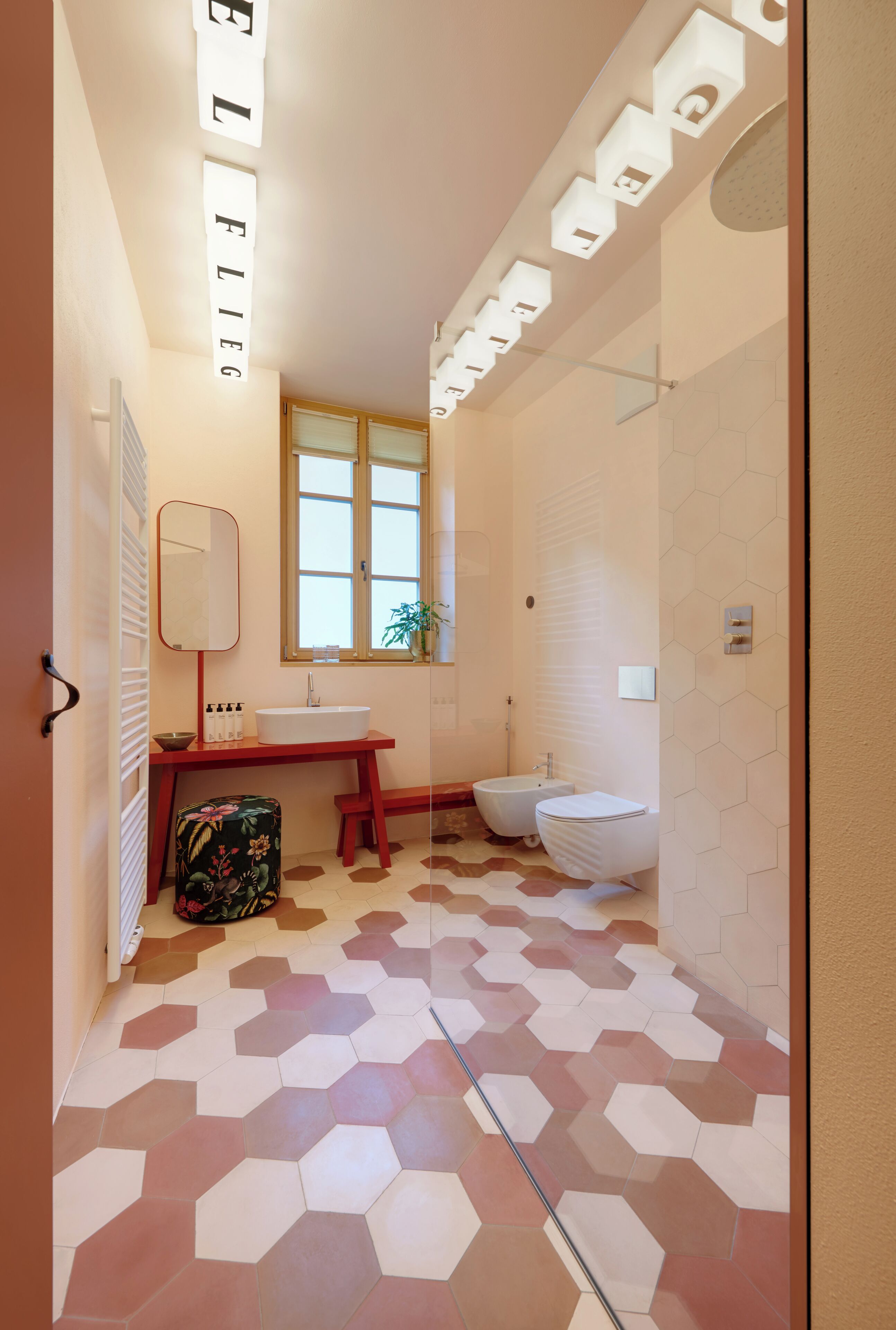 A modern bathroom with a hexagonal tile floor, a white sink, a mirror, and a toilet.