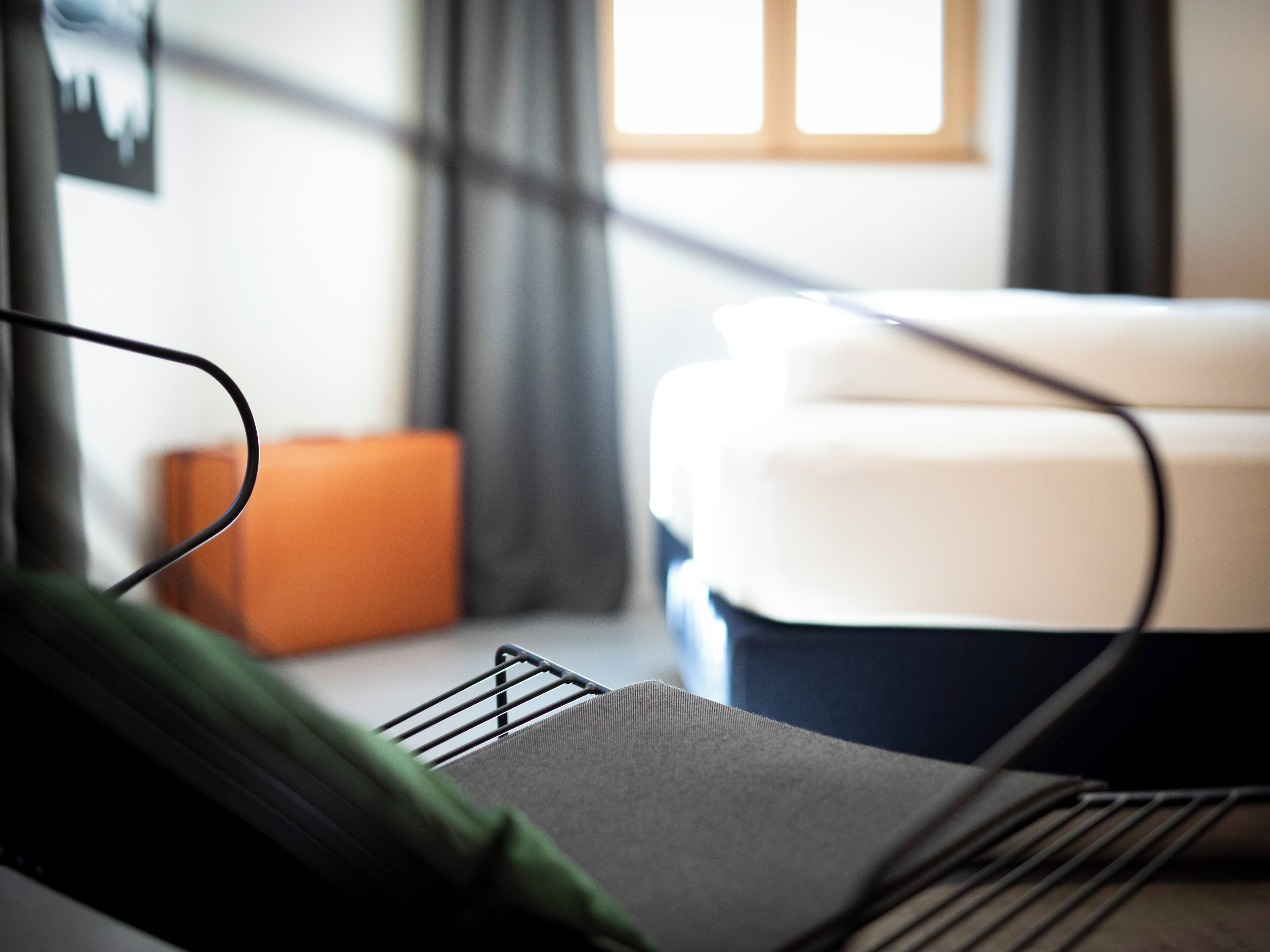 Une chambre d’hôtel bien rangée, avec un lit, une table de chevet et une fenêtre avec des rideaux.