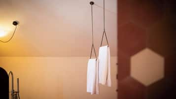 Un baño con una bañera blanca, un perchero de toallas blanco en la pared y una lámpara sobre el lavamanos.