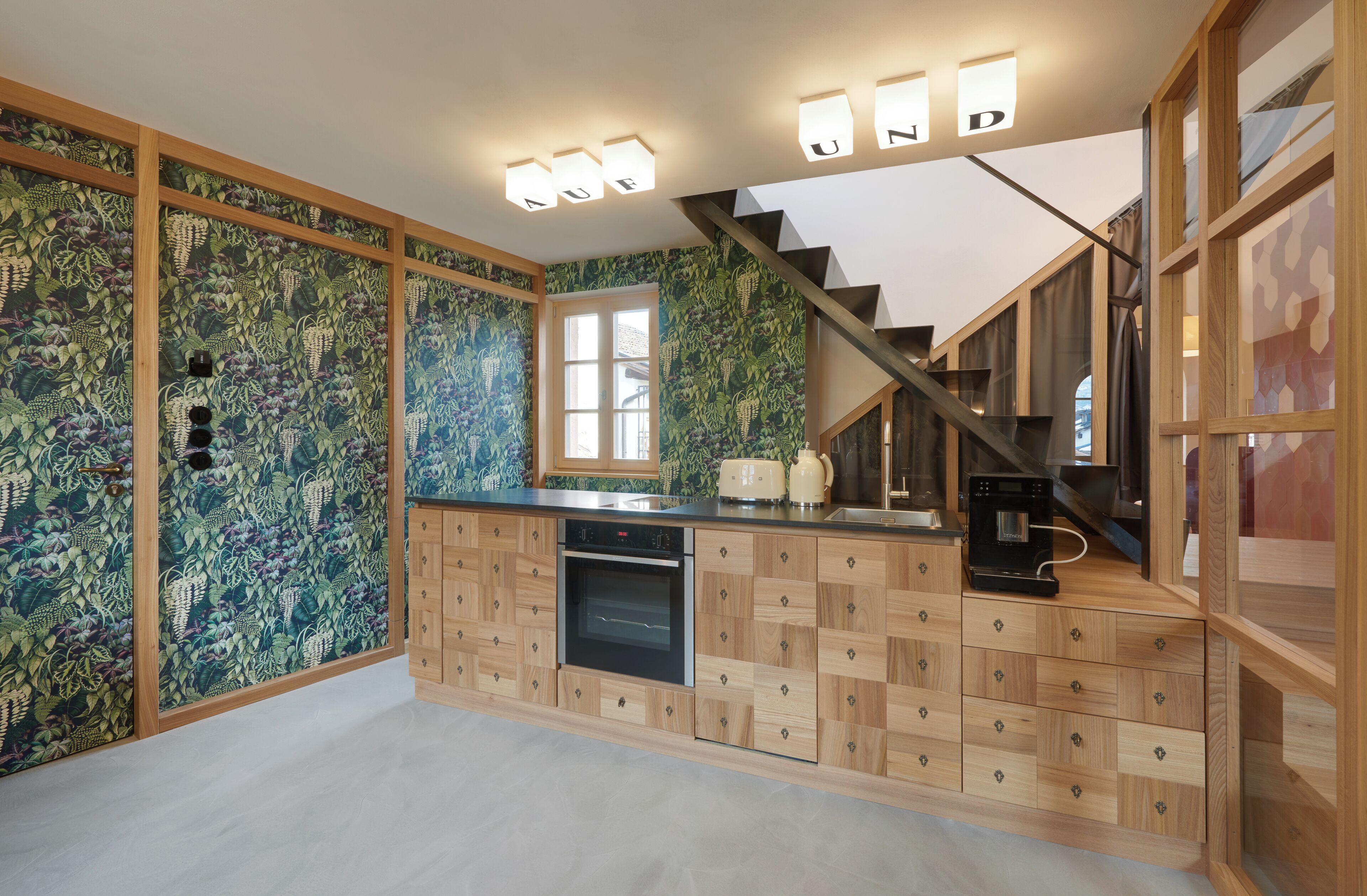 A modern kitchen with wooden cabinetry, a built-in oven, and a toaster.