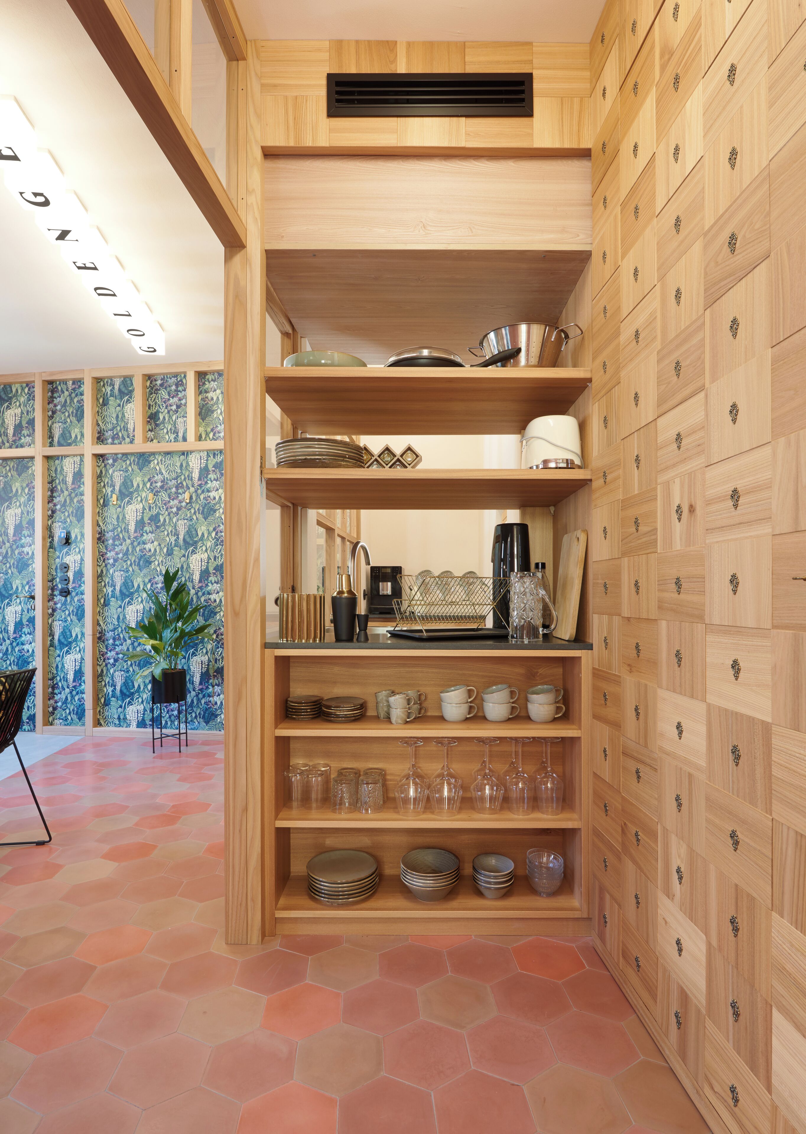 A kitchen with wooden cabinetry, a built-in stove, and a variety of kitchenware.