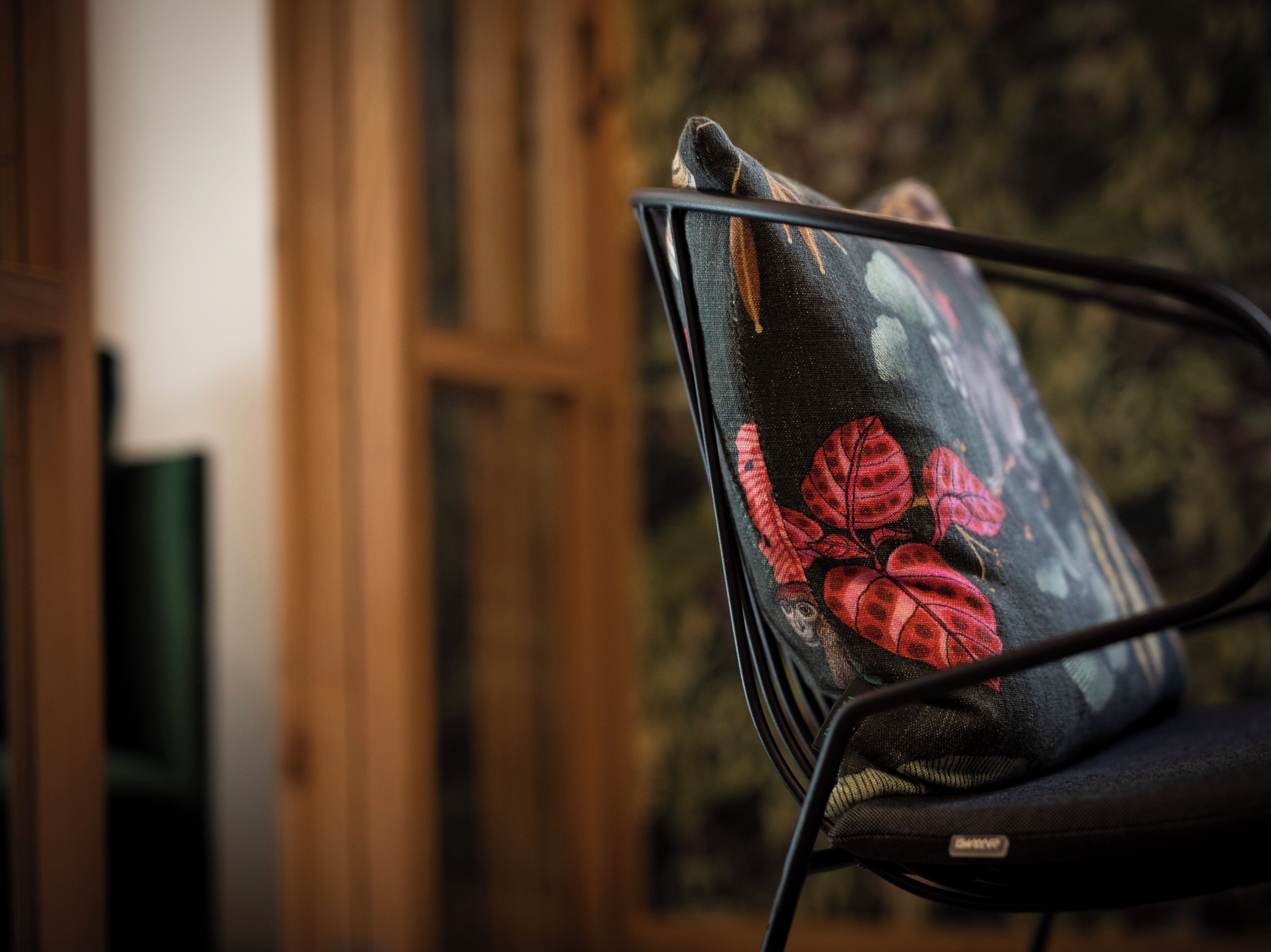 Una silla con un cojín estampado con flores, una puerta de madera y un fondo desenfocado.