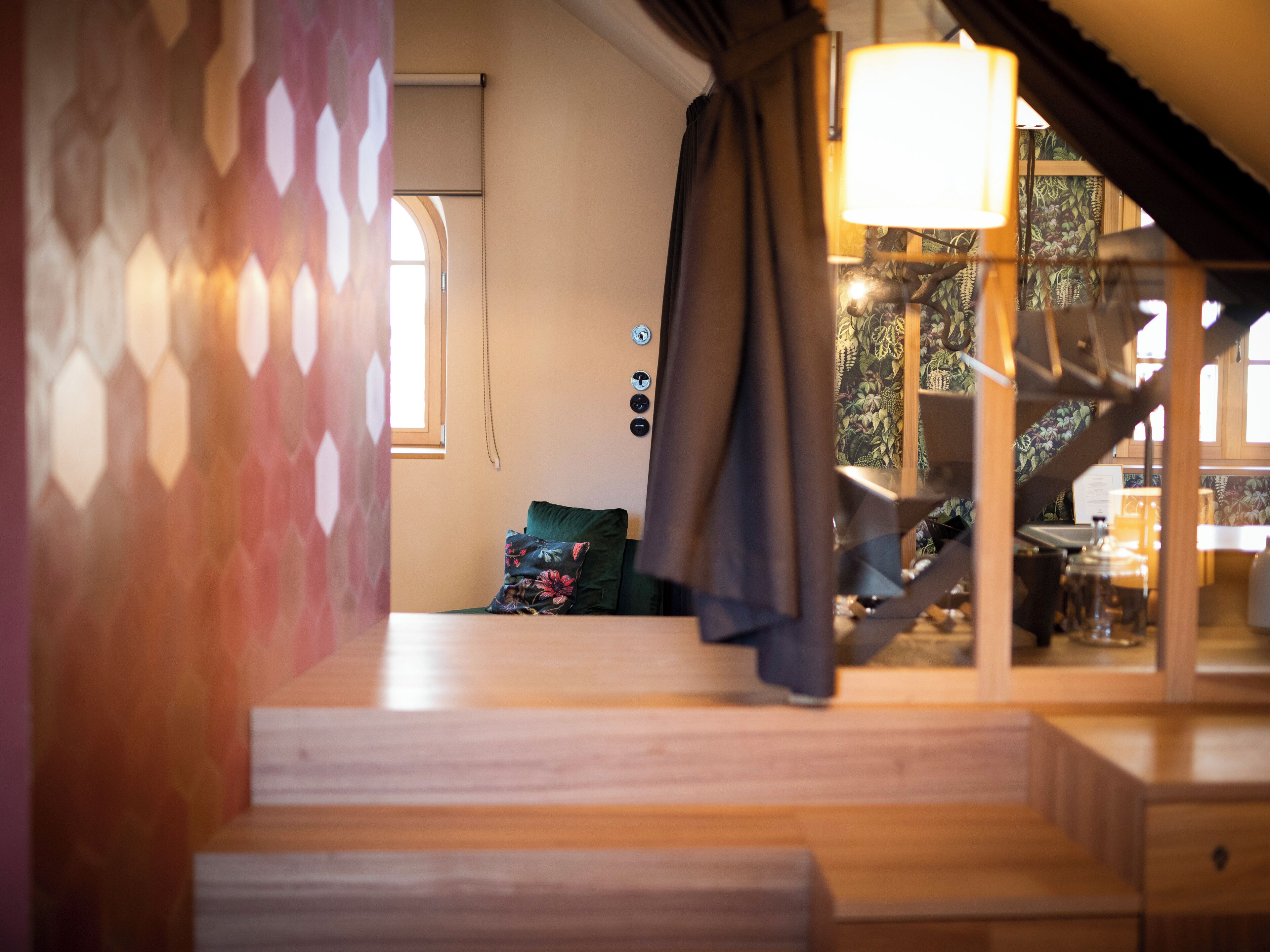 A staircase leading to a room with a window, a lamp, and a patterned wall.