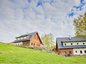 Et rustikt hotel i træhuse med flere bygninger, en græsbeklædt skråning og en klar himmel.