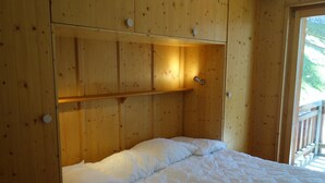 Une pièce en bois avec un lit, une étagère et une porte.