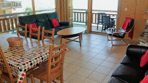 Une pièce chaleureuse comprenant une table à manger, des chaises, un canapé et un balcon également équipé de chaises.