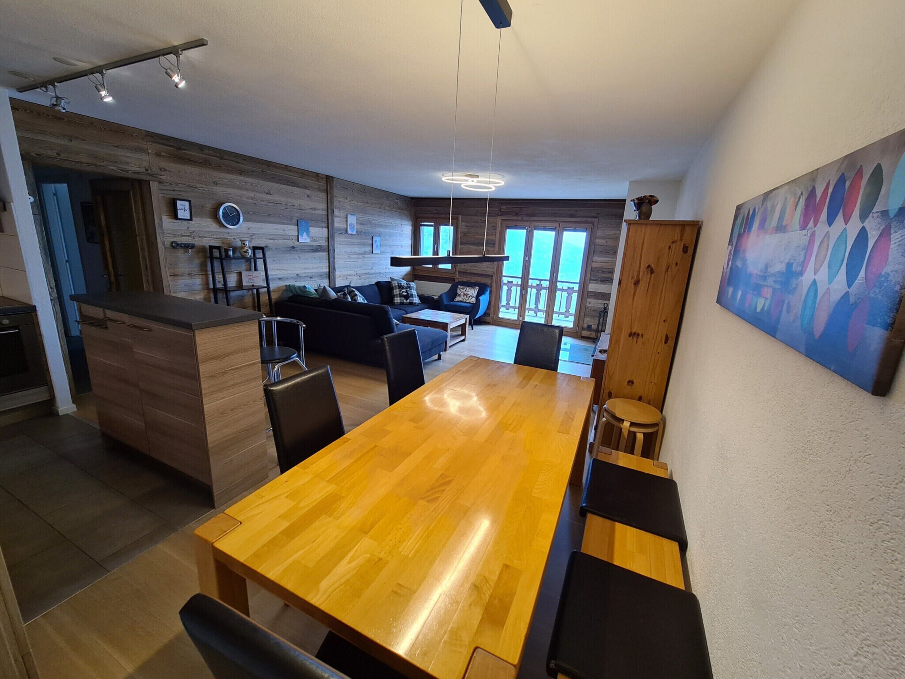 Eine moderne Küche mit Holzschränken, einer zentralen Kochinsel und einem Essbereich mit Holztisch und Bänken.
