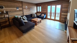 A cozy living room with a wooden wall, a sofa set, a coffee table, and a TV. - Mountain Apartment With Parking (Veysonnaz)