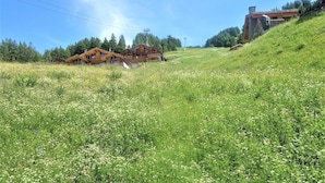 A hillside with wooden cabins and a stone building, surrounded by greenery and a clear sky. - Pleasant Apartment With View (Veysonnaz)