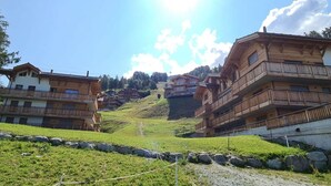 A mountainous village with wooden buildings, a clear sky, and a bright sun. - Pleasant Apartment With View (Veysonnaz)