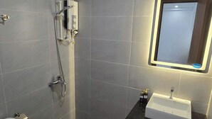 A modern bathroom with grey tiles, a white sink, a handheld showerhead, and a toilet. - Ha Bao Chau Hotel Tan Binh (Ho Chi Minh City)
