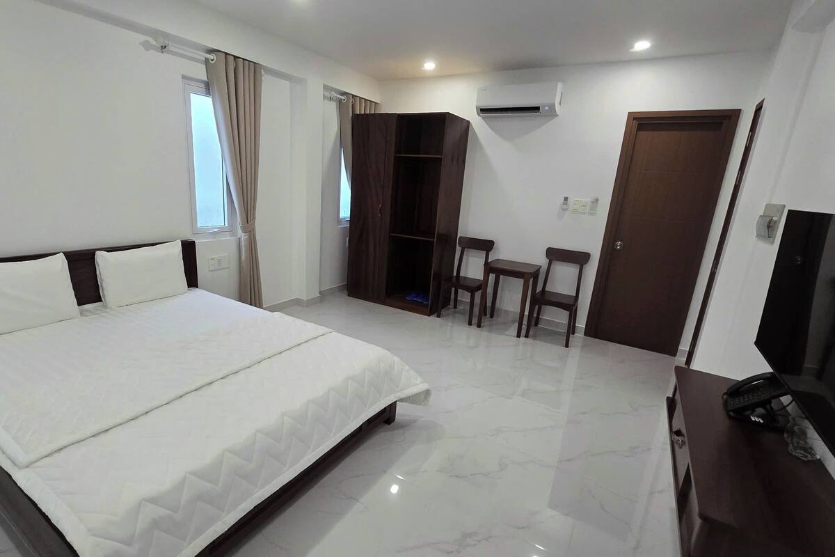 A hotel room with a bed, a wardrobe, a desk, and a TV.
