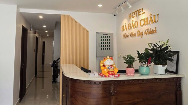 A hotel reception area with a wooden reception desk, a reception counter, and a reception desk with a sign above it. - Ha Bao Chau Hotel Tan Binh (Ho Chi Minh City)