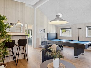 A modern living room with a pool table, bar area, and seating.