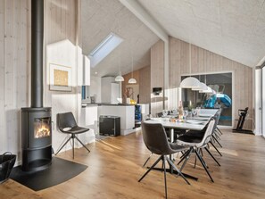 A modern kitchen with a central island, a dining area with a large table and chairs, and a wood-burning stove.