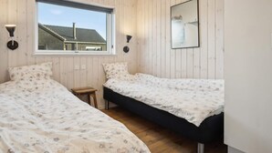 Une chambre avec deux lits, une fenêtre et un tableau encadré au mur.