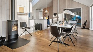 Eine moderne Küche mit einer zentralen Kochinsel, einem Essbereich mit großem Tisch und Stühlen sowie einem Holzofen.