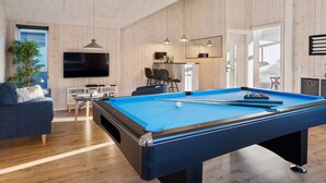Un salon moderne comprenant une table de billard, un canapé, un téléviseur et un coin repas.