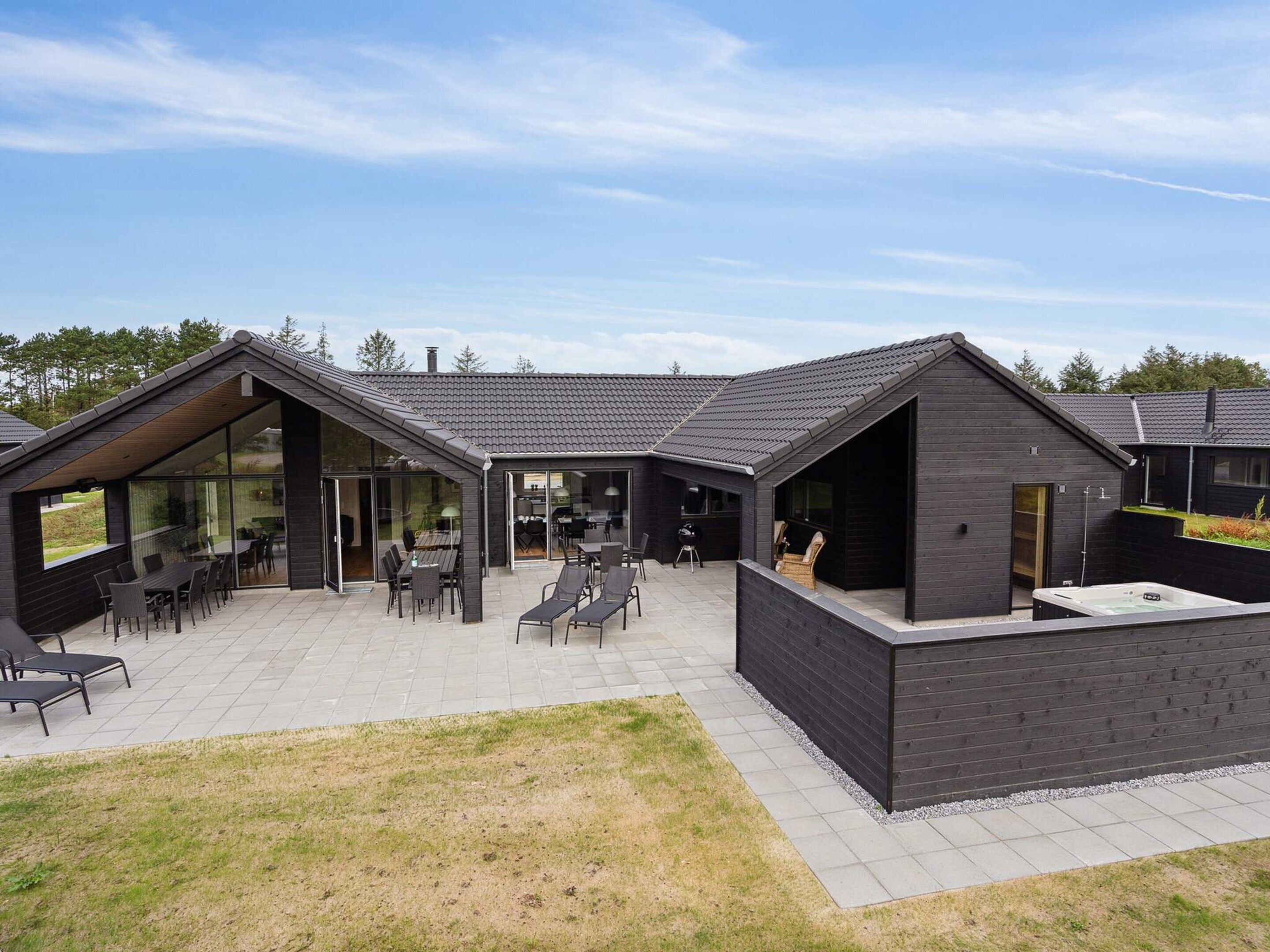 Ett modernt hus med en uteplats som har utemöbler och en bubbelpool.