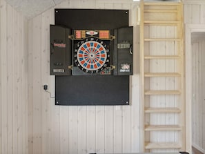 Eine Dartscheibe an einer Wand, daneben eine Holzleiter.