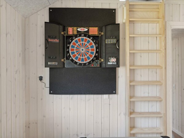 A dartboard mounted on a wall with a wooden ladder to its right.