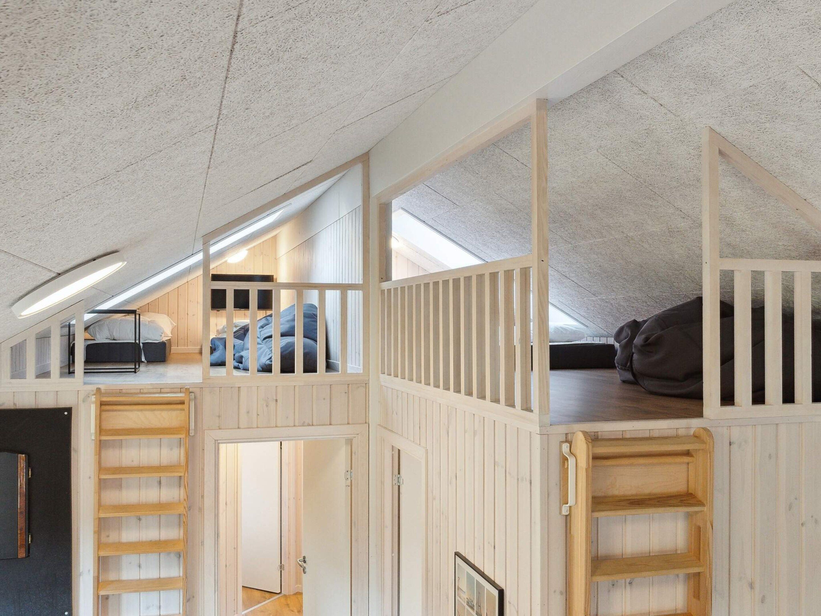 A loft bedroom with a sloped ceiling, wooden bunk beds, and a skylight.