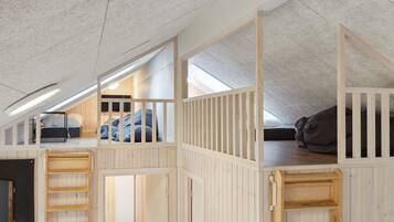 A loft bedroom with a sloped ceiling, wooden bunk beds, and a skylight.